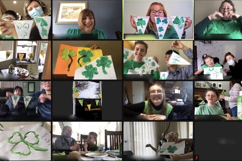 Photo of a Zoom virtual platform screen with collage of 16 photos of people holding up their St. Patrick’s Day green shamrock paintings for their Zoom activity.